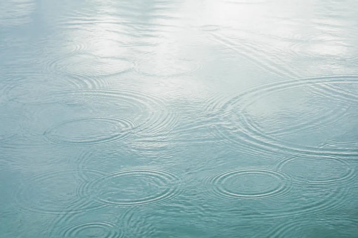 Soft circular ripples across pale blue pond water